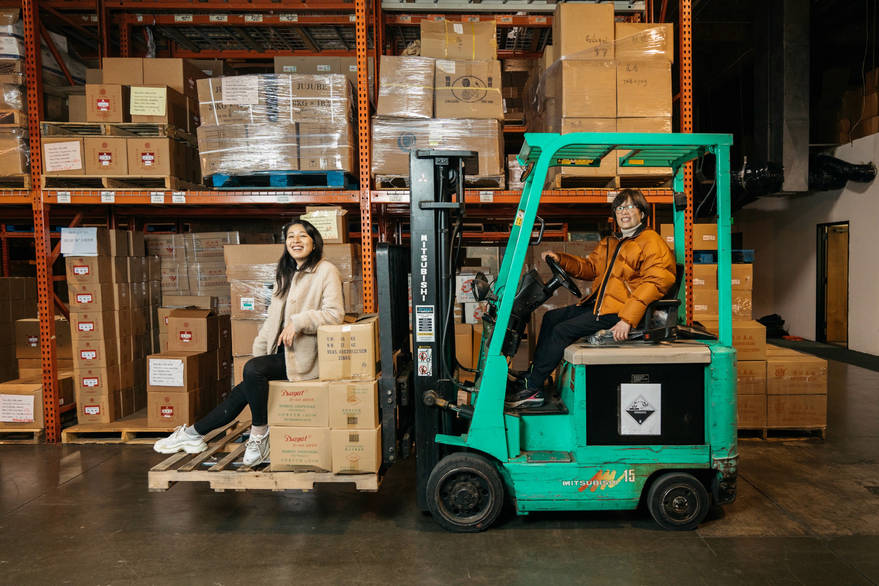 Two team members on a forklift in the warehouse