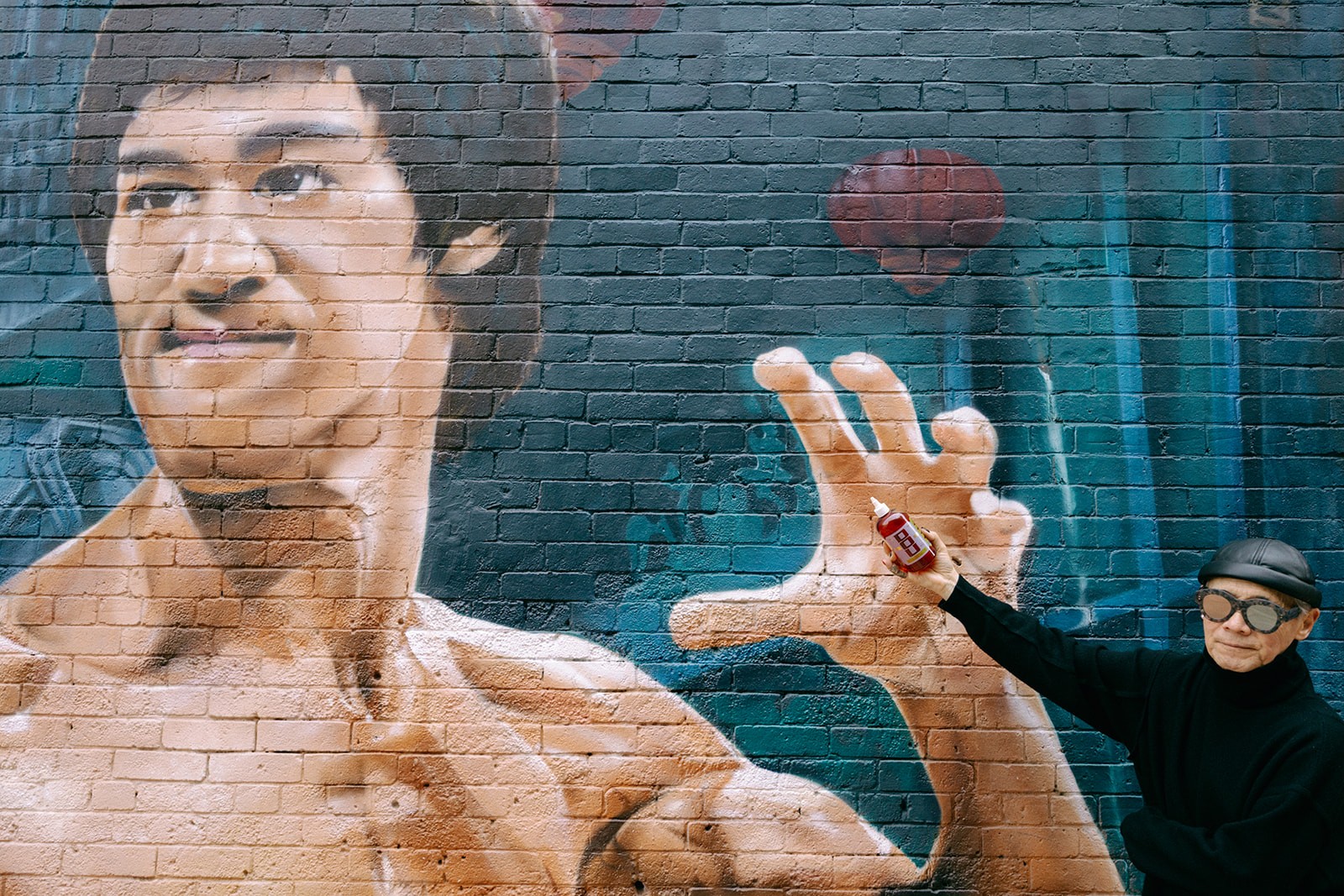 A mural of Bruce Lee with a bottle of sauce in hand